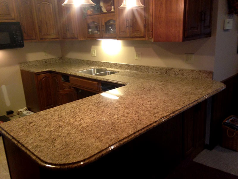 Earthtones create a warm inviting kitchen with Giallo Ornamental Granite and medium brown cabinets.