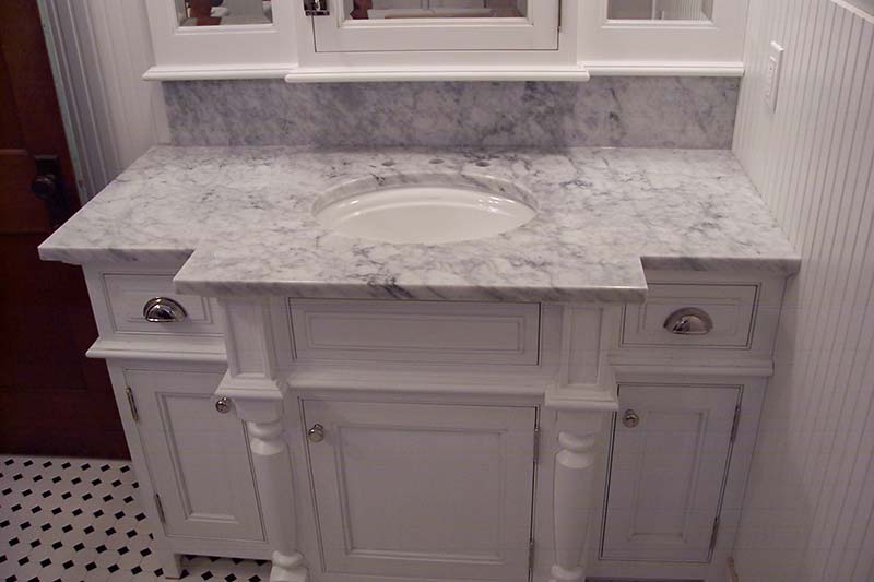 Italian White, or Carrara Marble bathroom counter looking very classical over a white columned vanity.