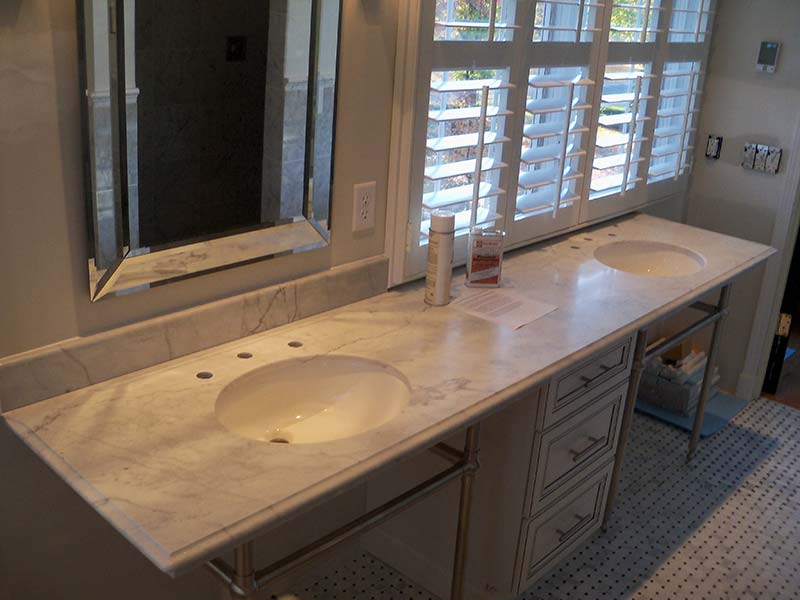 Italian White Marble with double sinks over white cabinets.