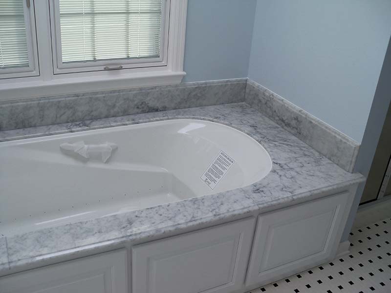 Italian White Marble tub deck over white cabinets contrasted by light blue bathroom walls.
