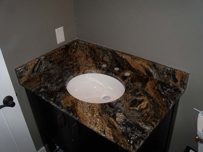 This bathroom counter of Magma Granite shows the high contrast colors of gold, dark grey, off white, and black.