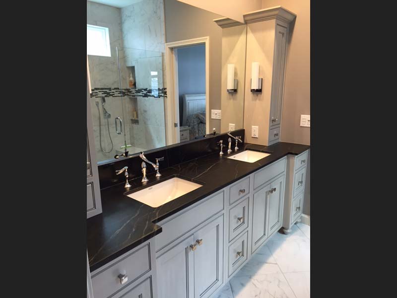 Dark oiled Soapstone counter with contrasting white double sinks looks great above the light bathroom vanity.