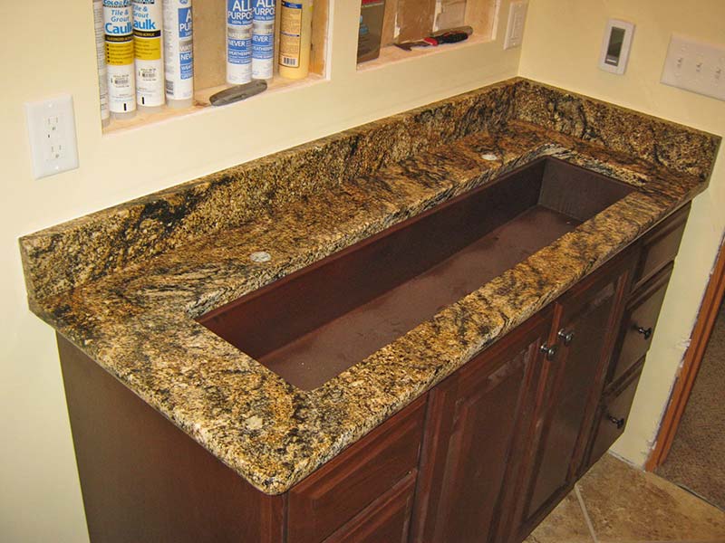 The movement of golds and blacks in this Stormy Night laundry room counter with a brown trough sink makes this project very unique.