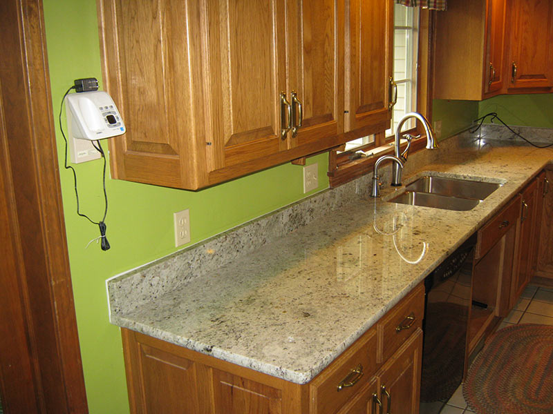 Colonial White Granite kitchen counter with medium brown cabinets.