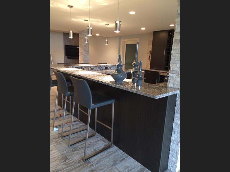 Diamond Wave Granite bar with dark wood cabinets.