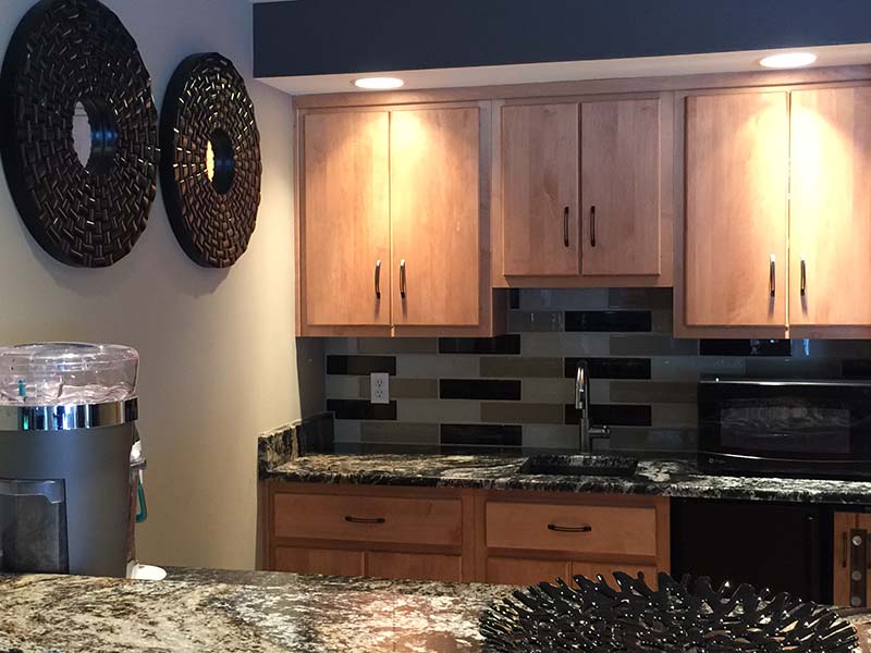 Diamond Wave Granite kitchen counter with medium wood toned cabinets and black accents. 