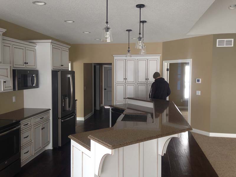 Quartz kitchen island surround by white cabinets and earthtone walls.