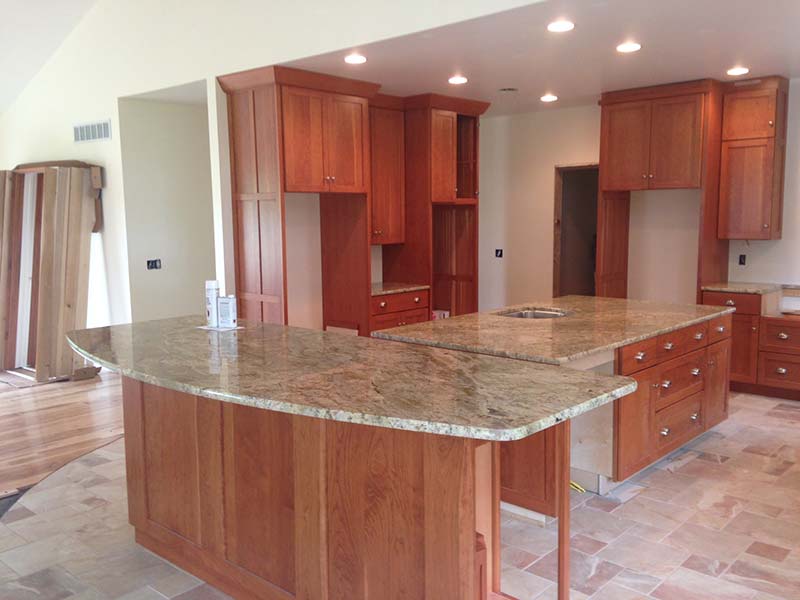 Typhoon Bordeaux Granite kitchen counter and island with warm medium toned cabinets.